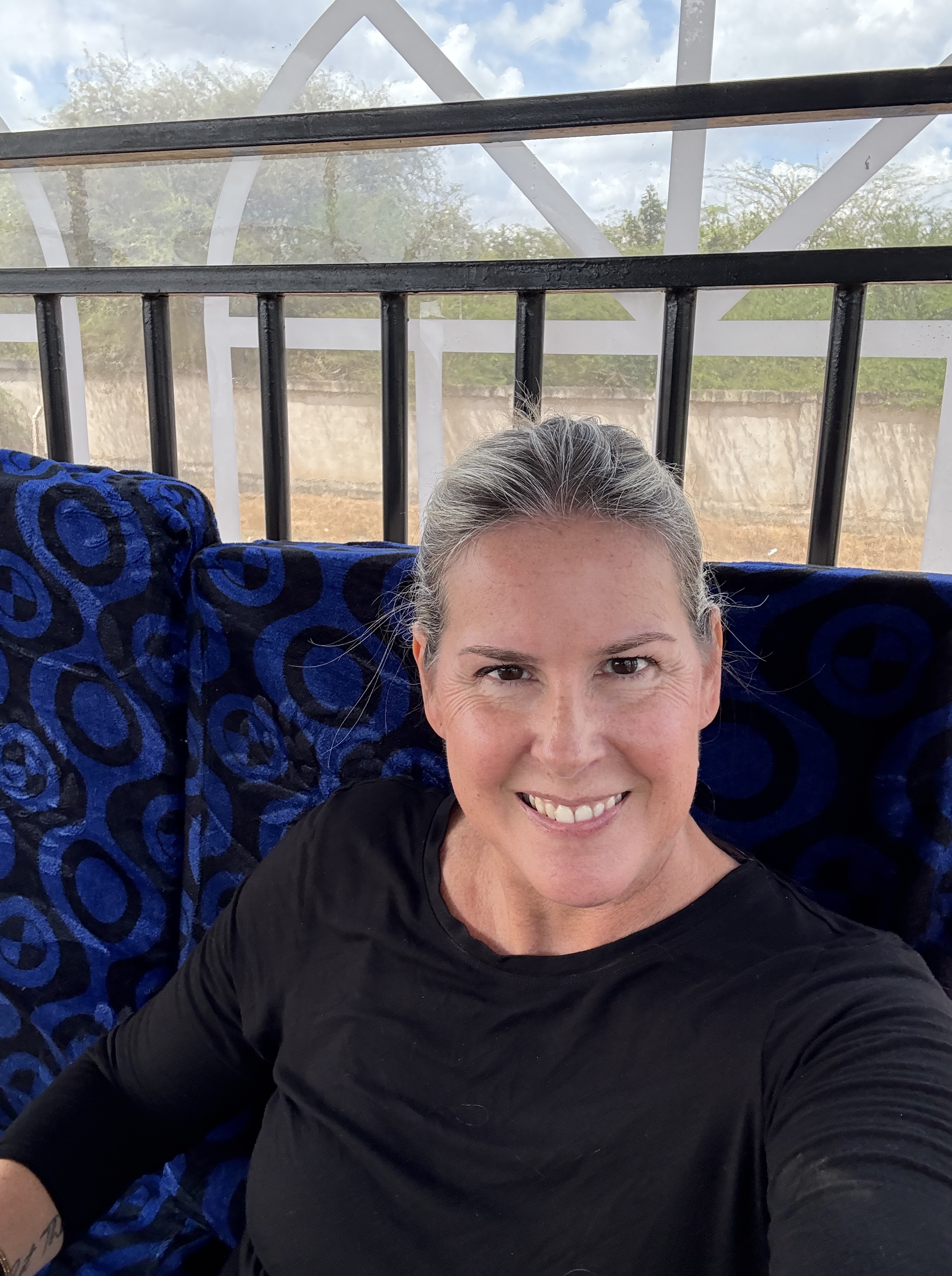 Blonde woman sitting on a blue couch with her hair pulled back.